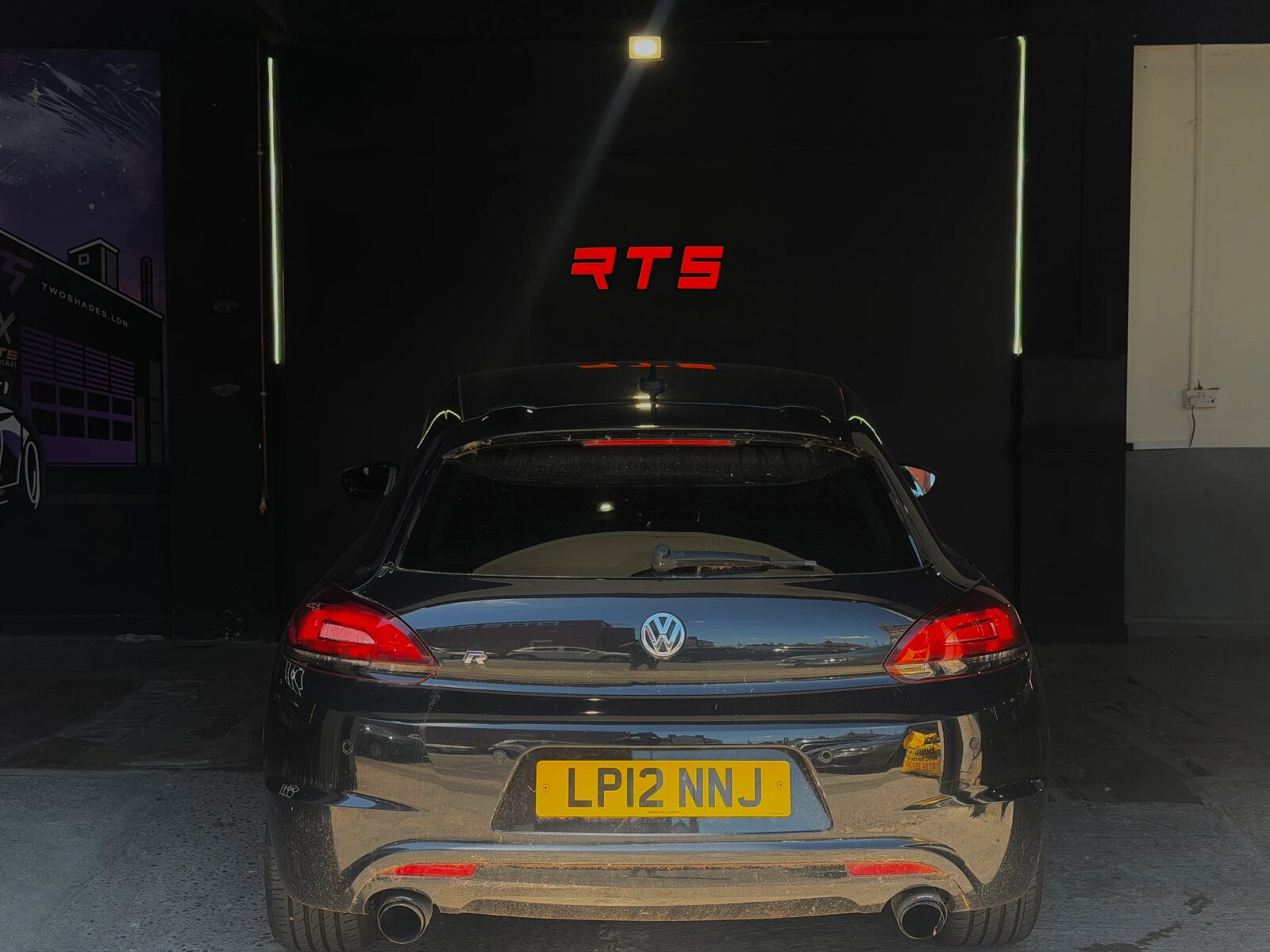 Volkswagen Scirocco R beneath the glowing RTS workshop sign